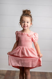 Young girl wearing a pink dress against a plain background